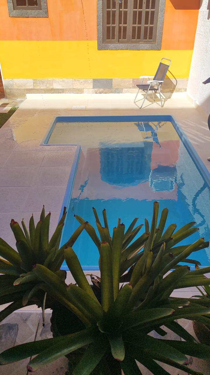 Piscina em L com borda atérmica clara e paredes coloridas